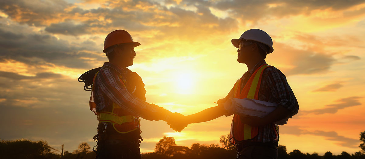 Men shaking hands with sunset behind them